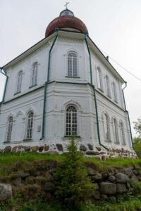 Белый храм Вознесения на Секирной горе стоит над каменным основанием у обрыва
