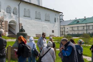 Туристы у монастырской стены Соловков, экскурсия возле колокола