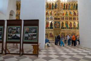 Иконостас и золотая люстра, экскурсанты рассматривают ряды икон
