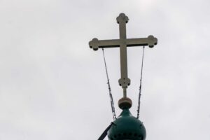 Крест на куполе храма на Секирной горе под серым небом Белого моря